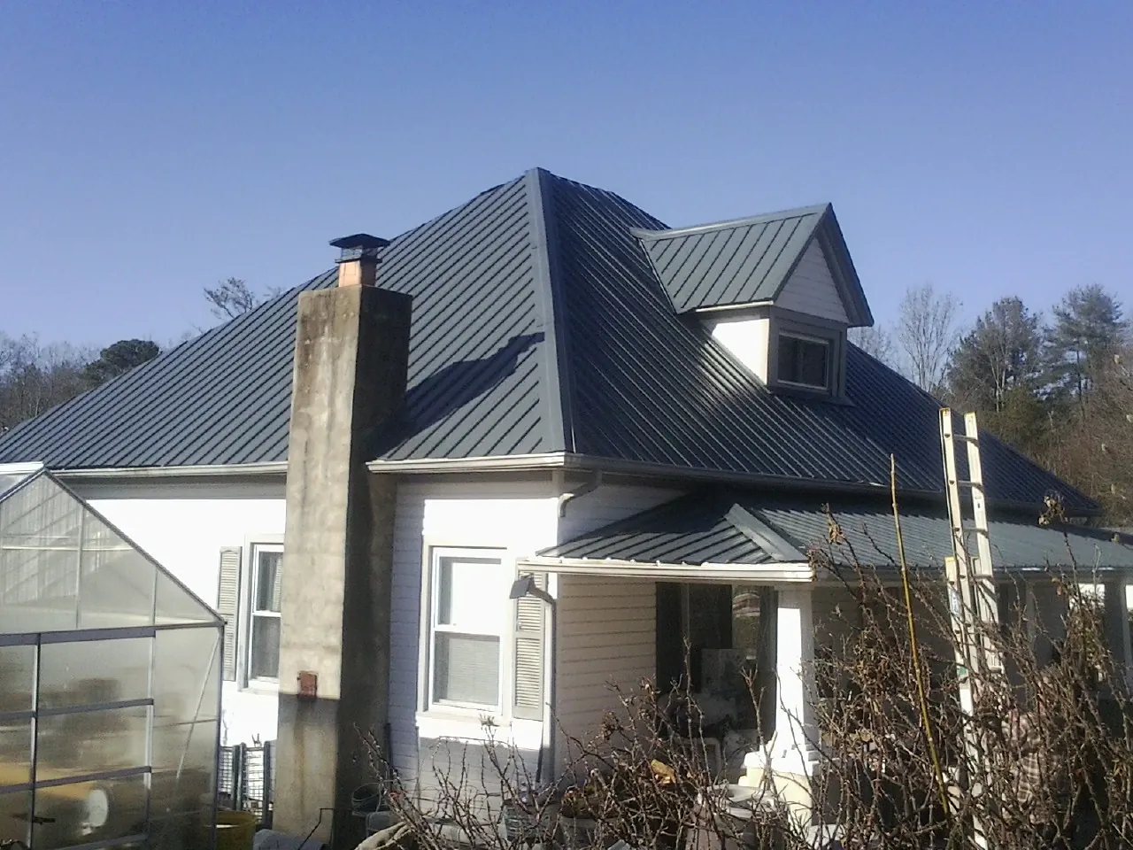 Dark blue standing seam metal roof on a white farmhouse with dormer — Slate & Tile Roof Repair by Roofing Brothers in Florence