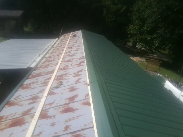 Old rusted panels beside newly installed green metal roofing — Wind Damage Roof Repair by Roofing Brothers in Florence