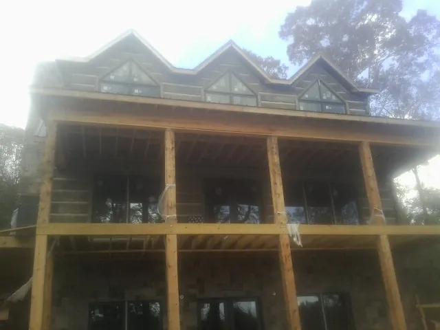 Dormers and porch framing on a large log home under construction — Roof Coating work by our crew in Florence